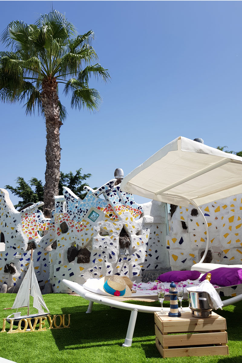Terraza con tumbona, sombrero y palmera en jardín del lugar en Tenerife. Texto: I LOVE YOU.