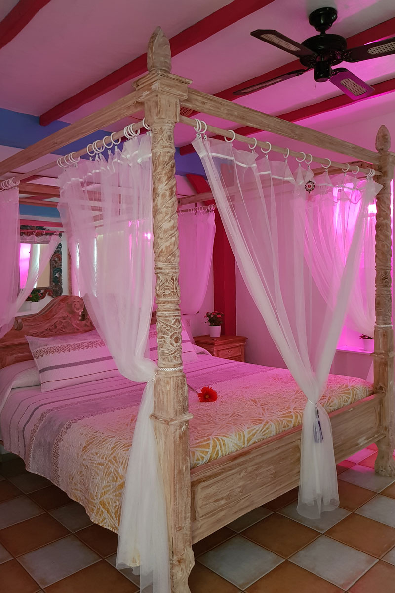 Cama con dosel y luces rosas en una habitación en Tenerife.