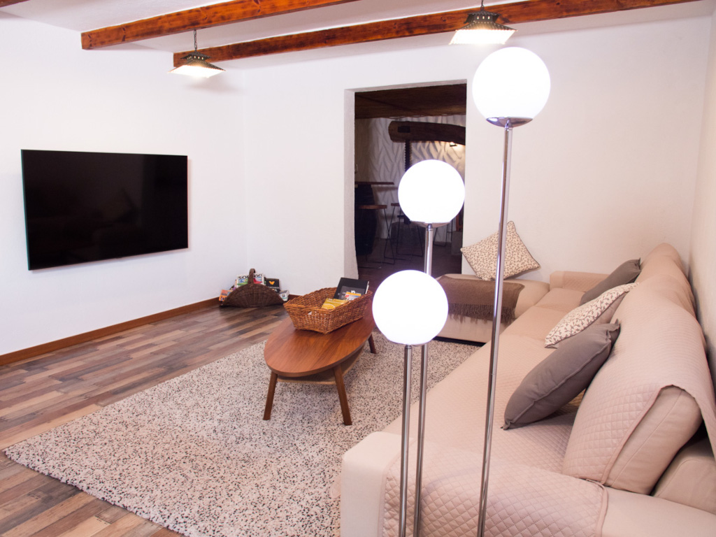 Sala de estar con sofá, televisor montado en la pared y lámpara de pie en Tenerife.