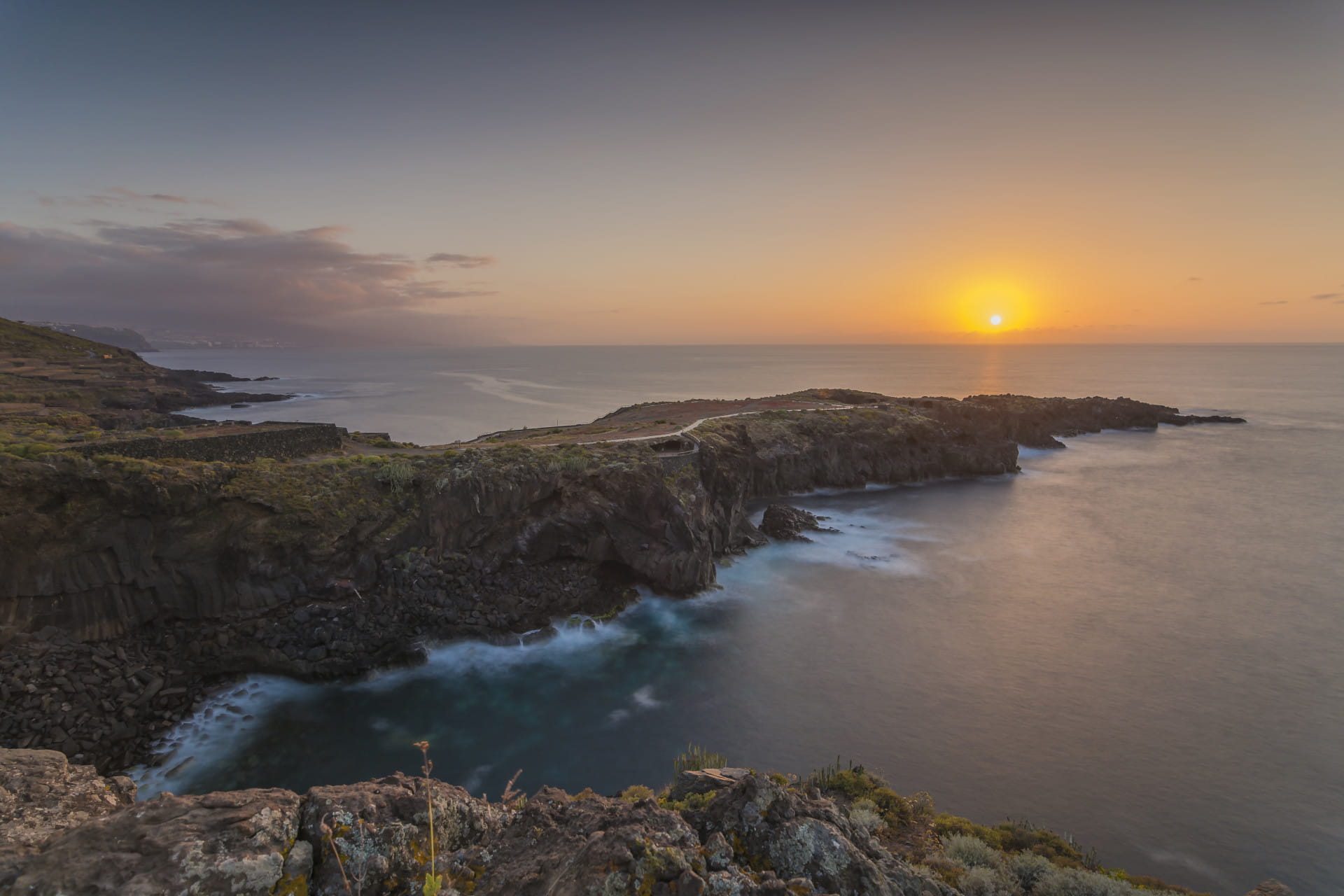 Atardecer en la costa de Tenerife con acantilados y mar en el horizonte.
