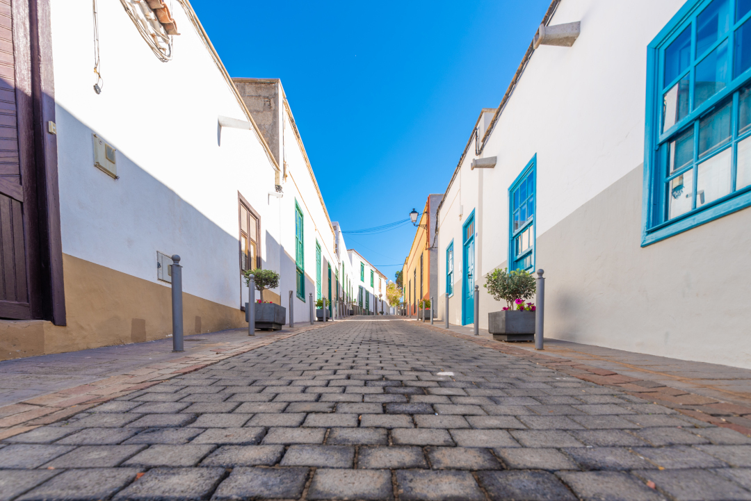 Calle empedrada entre casas blancas con ventanas azules en Tenerife.