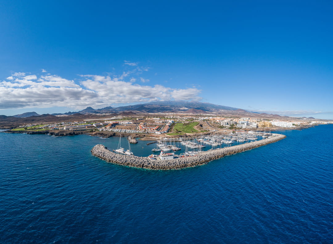 Vista aérea del puerto deportivo en Tenerife con montañas al fondo.