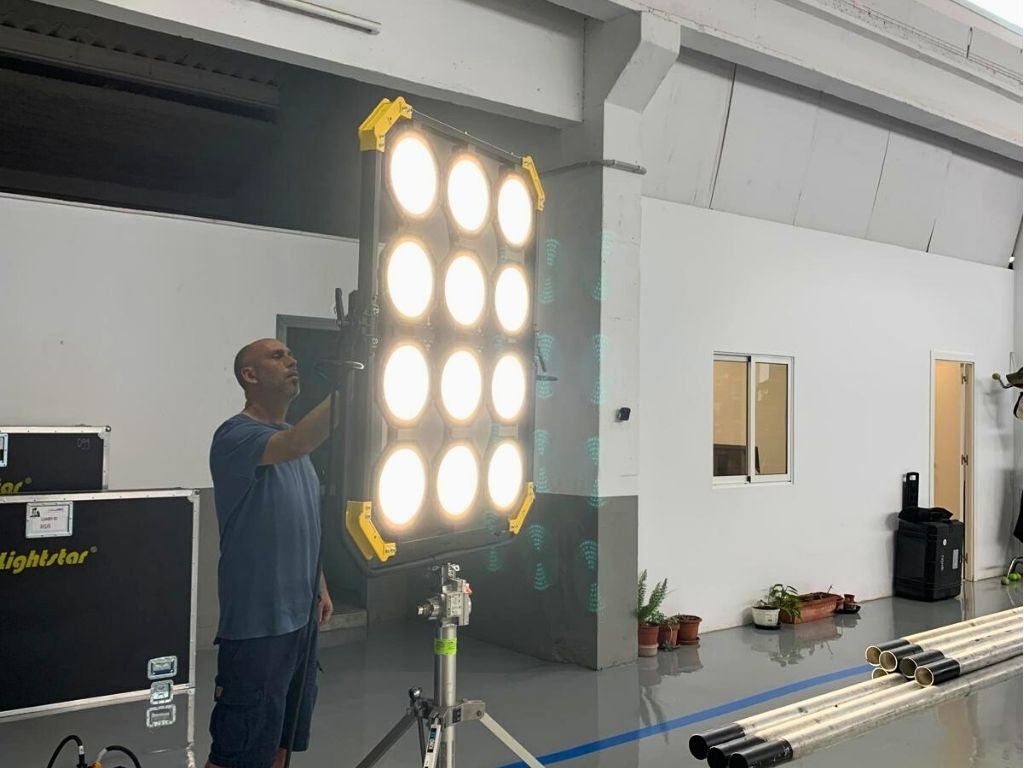 Hombre ajustando lámpara grande en estudio de producción en Tenerife.
