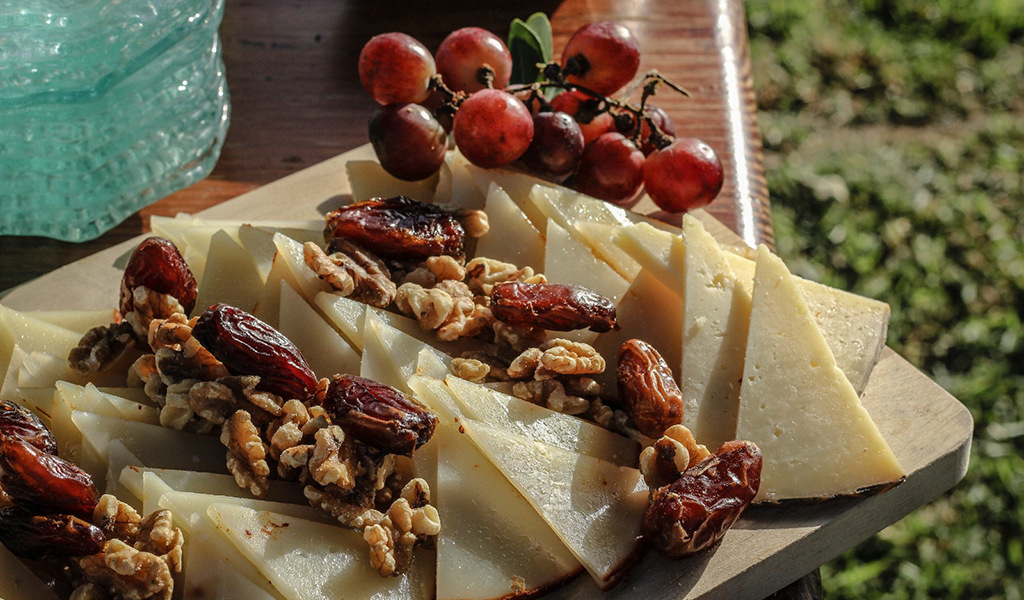 Queso tinerfeño en tabla con nueces, dátiles y uvas rojas en Tenerife.