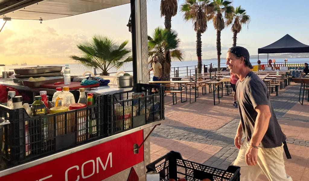 Vendedor ambulante en paseo marítimo de Santa Cruz de Tenerife al atardecer.
