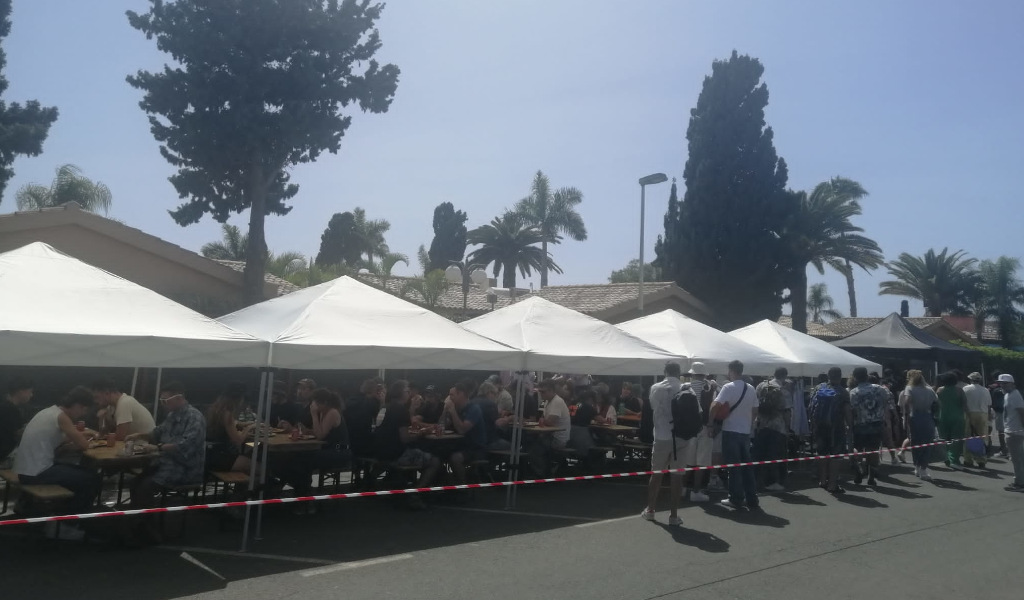 Personas almorzando bajo carpas en un evento al aire libre en Tenerife.