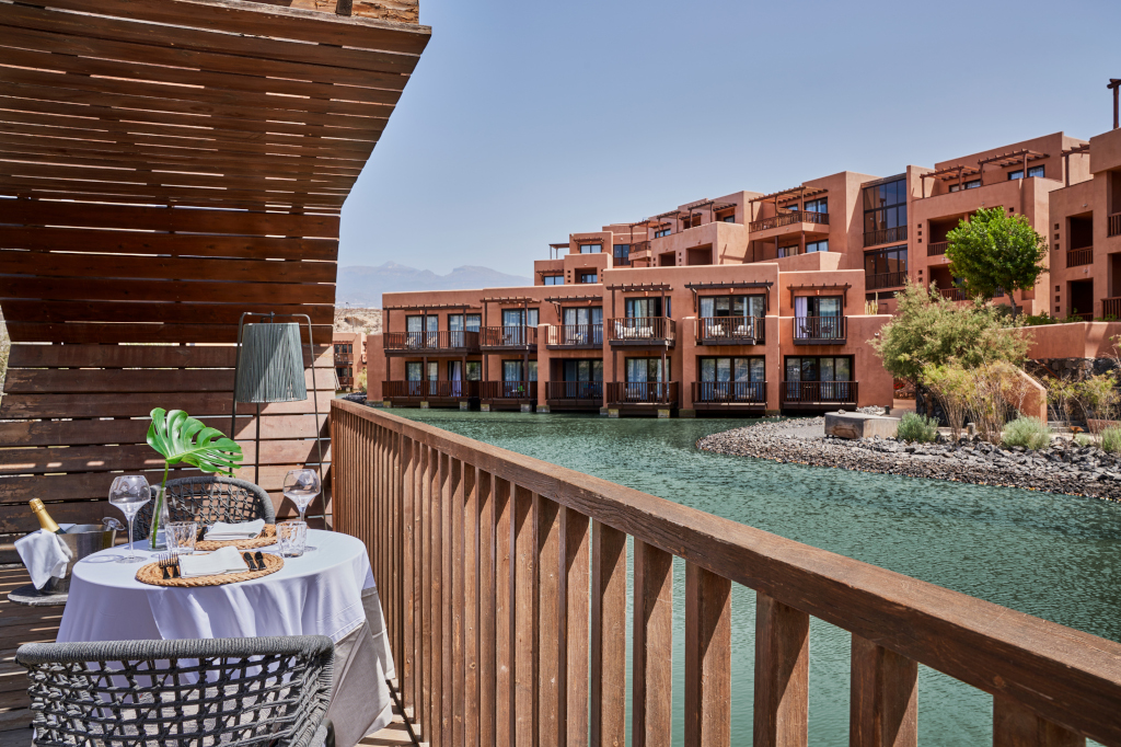 Terraza con mesa y sillas junto a un canal de agua en un complejo turístico en Tenerife.