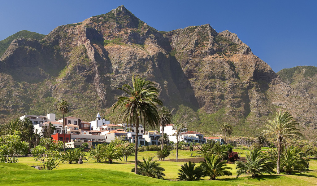 Paisaje montañoso con palmeras y edificios en Buenavista del Norte, Tenerife.