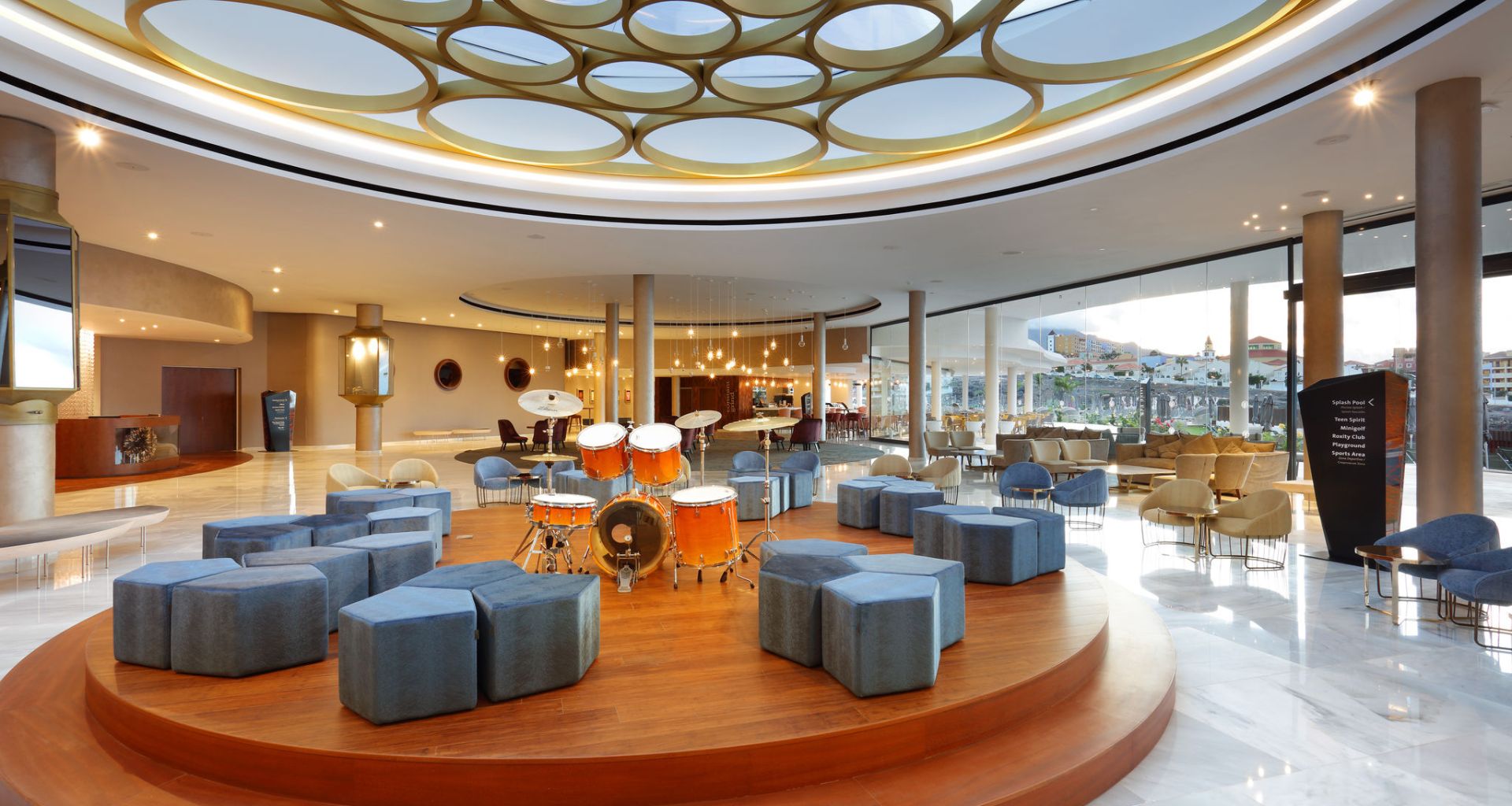 Lobby del hotel en Tenerife con batería en plataforma circular y techos modernos.
