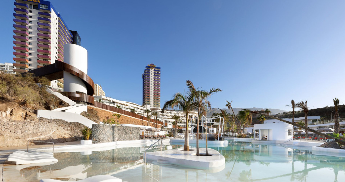 Piscina con palmeras y edificios de fondo en Costa Adeje, Tenerife.