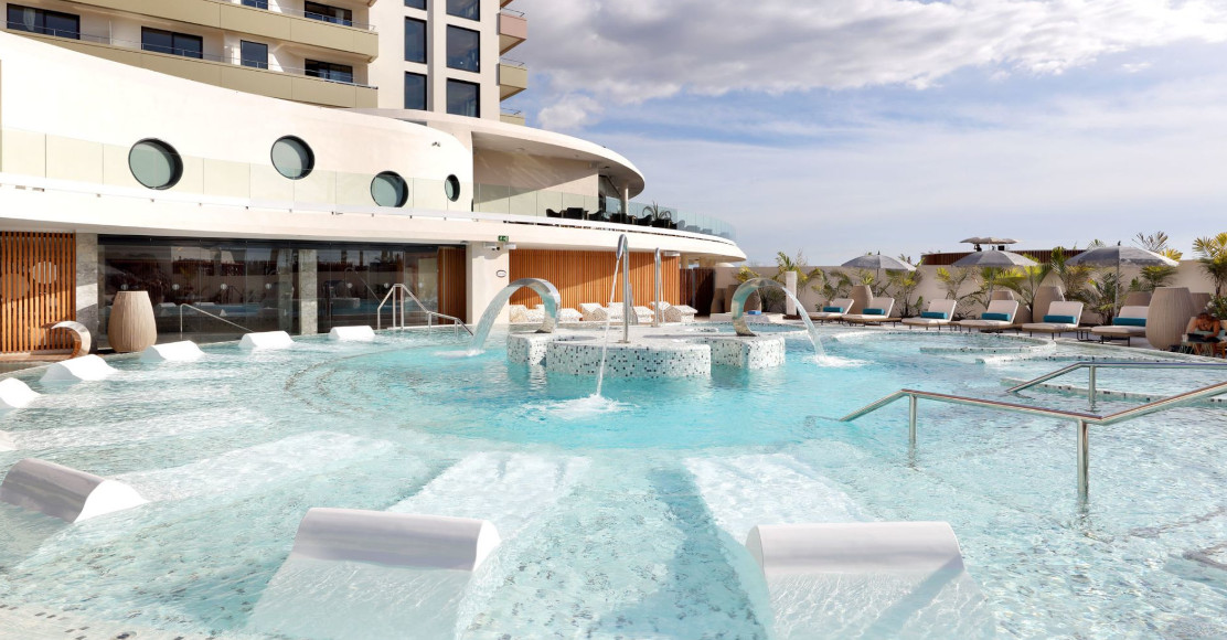 Piscina exterior del hotel en Tenerife con tumbonas y chorros de agua.
