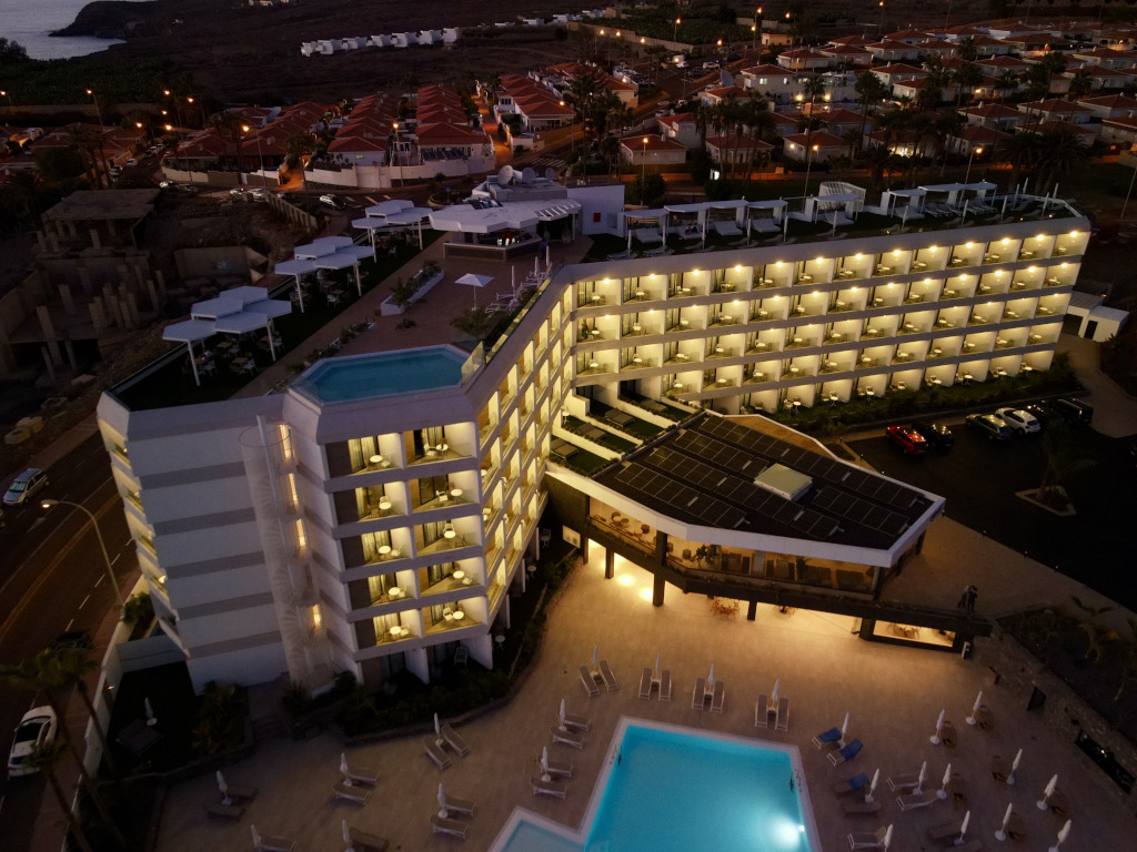 Edificio iluminado con piscina en la azotea en Tenerife al atardecer.