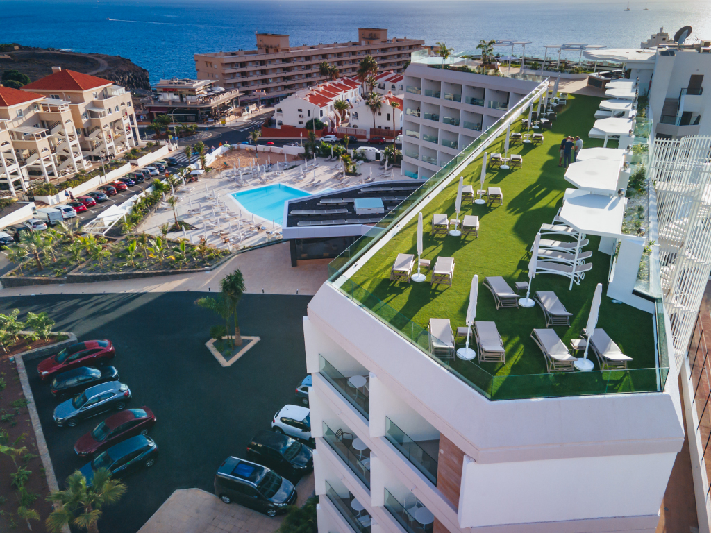 Terraza con tumbonas y sombrillas cerca de la piscina, costa de Tenerife al fondo.