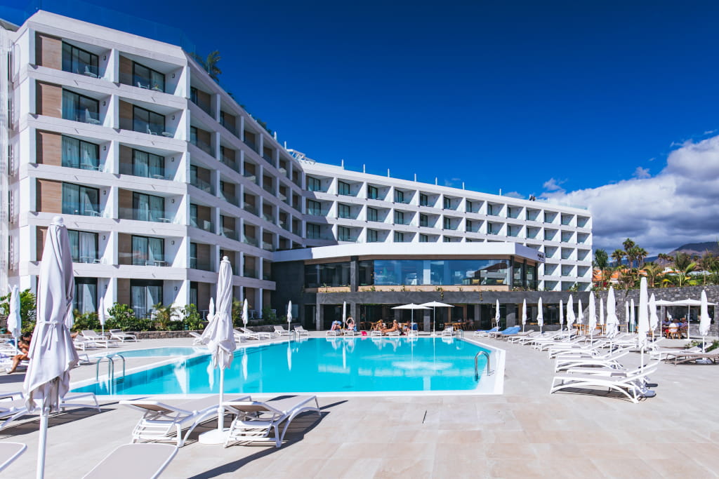 Hotel moderno con piscina y tumbonas en Costa Adeje, Tenerife.
