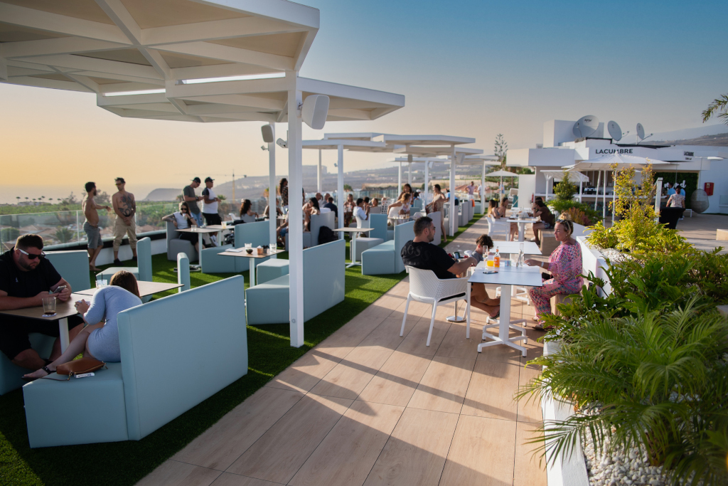 Personas en terraza al aire libre en La Cúspide, Tenerife, disfrutando al atardecer.