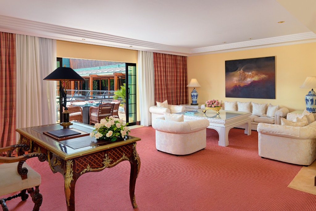 Sala de estar con escritorio de madera, sofás beige y puertas abiertas al exterior en Tenerife.