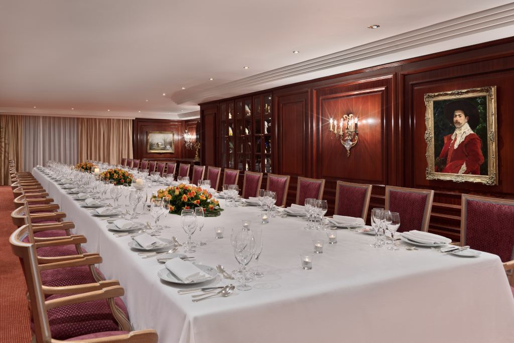Mesa de comedor elegante con sillas rojas y cuadros en una sala en Tenerife.