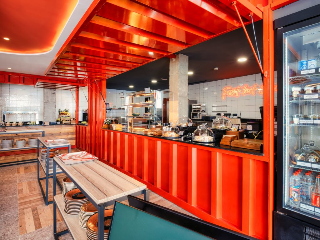 Interior de restaurante en Tenerife con mesas de madera y mostrador rojo.