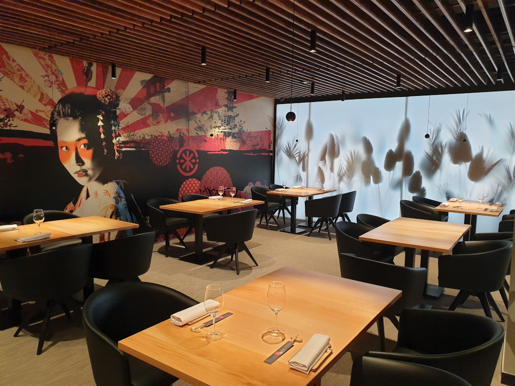 Restaurante con mesas de madera y mural de geisha en una pared en Tenerife.