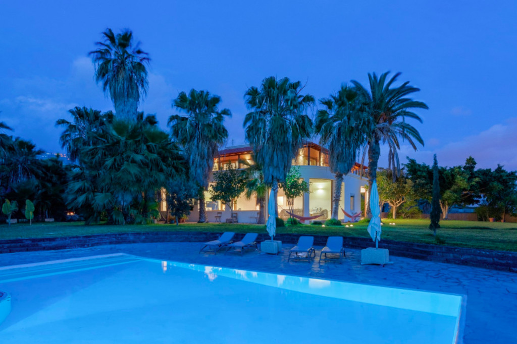 Casa con piscina y palmeras al atardecer en Tenerife.