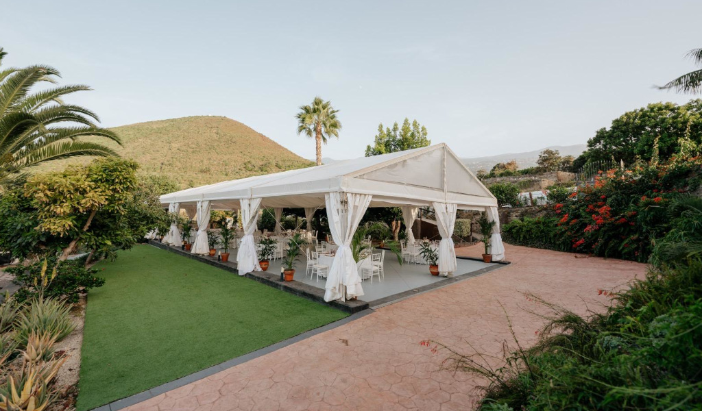 Carpa blanca en un jardín rodeado de vegetación en Tenerife.