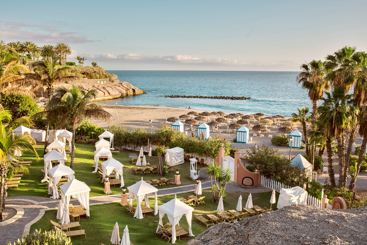 Playa con sombrillas y cabañas en Costa Adeje, Tenerife, al atardecer.
