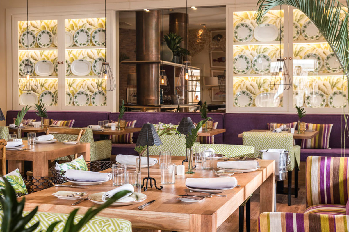 Restaurante en Tenerife con mesas preparadas y decoración floral en las paredes.