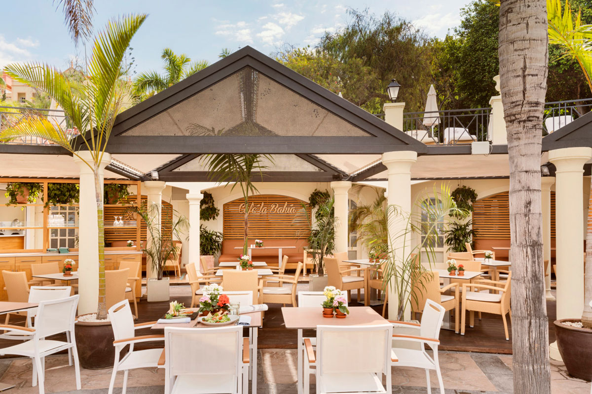 Terraza del Café La Bahía en Tenerife, con mesas y vegetación alrededor.