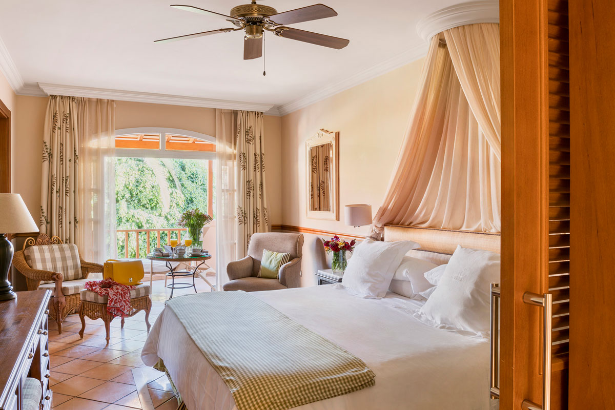 Habitación con cama grande, muebles elegantes y vista al jardín en Tenerife.