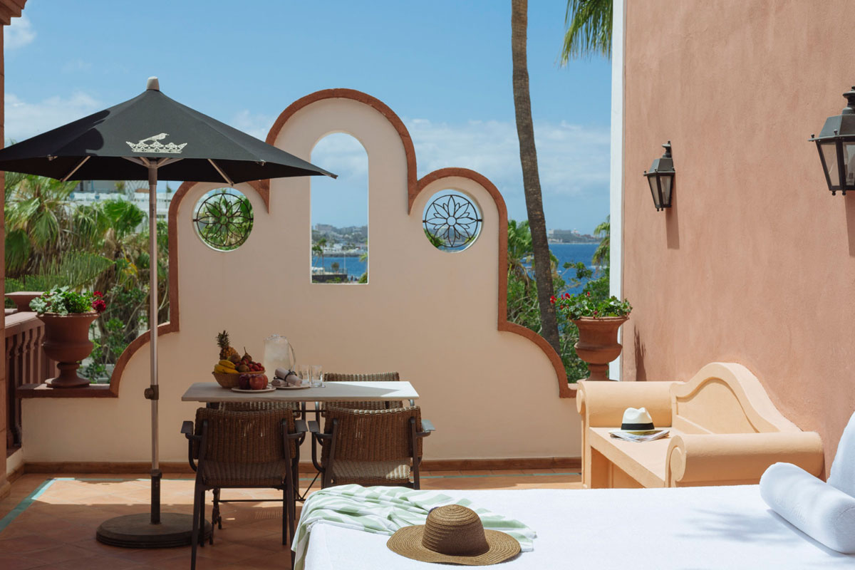 Terraza en Tenerife con mesa, sombrilla negra y vistas al mar de fondo.