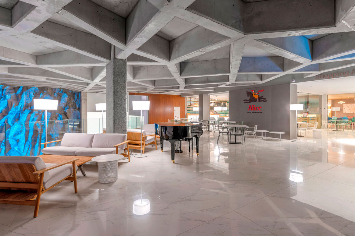 Lobby moderno con techo geométrico y piano en centro comercial Afiche, Tenerife.
