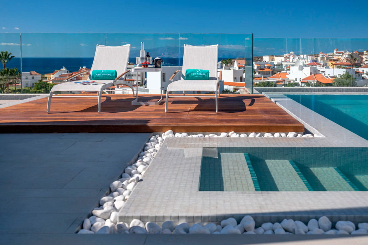 Tumbonas junto a una piscina con vista al mar y a la ciudad en Tenerife.