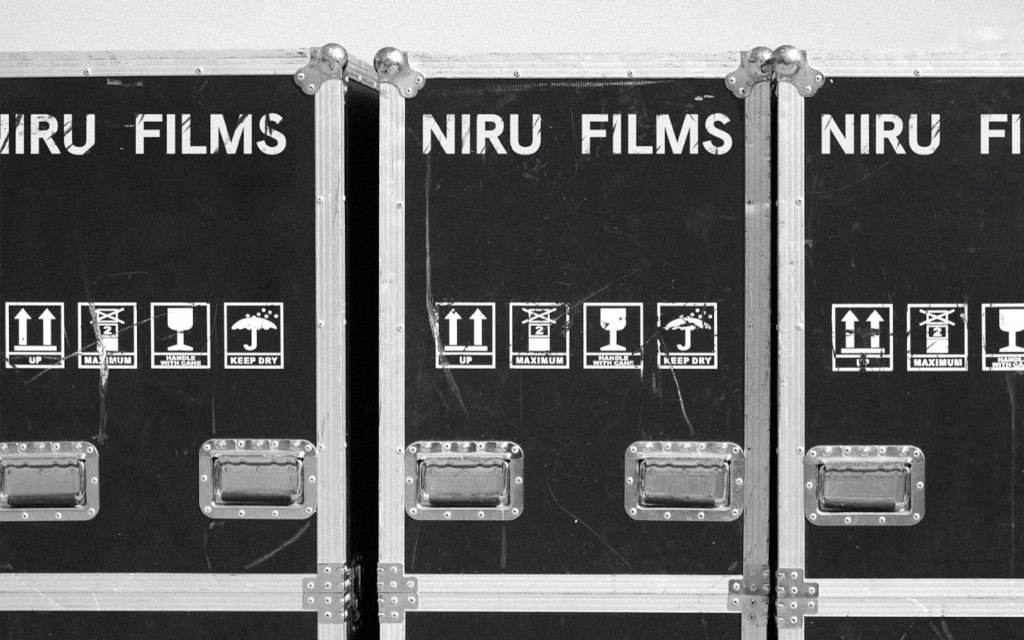 Cajas de transporte etiquetadas como Niru Films, con iconos de manejo.