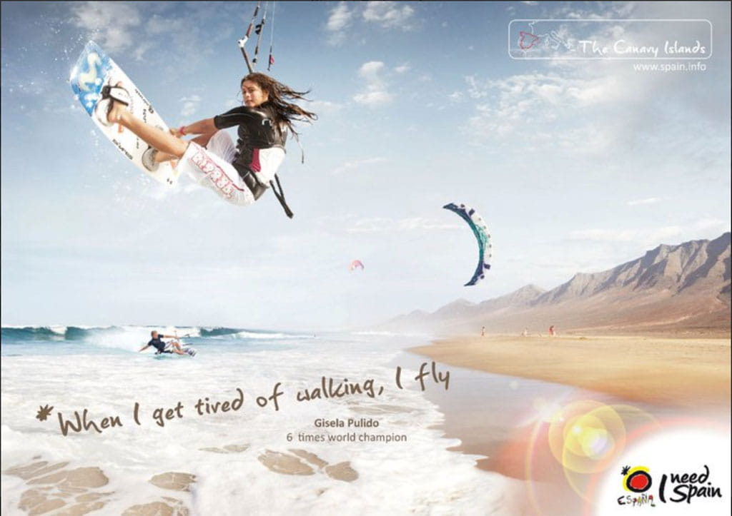Persona haciendo kitesurf en la playa de Tenerife con montañas al fondo. Texto: When I get tired of walking, I fly.
