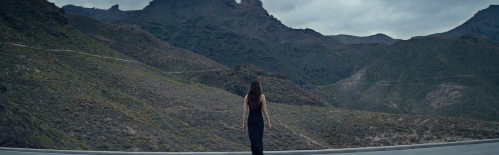 Persona caminando hacia las montañas en Tenerife bajo un cielo nublado.