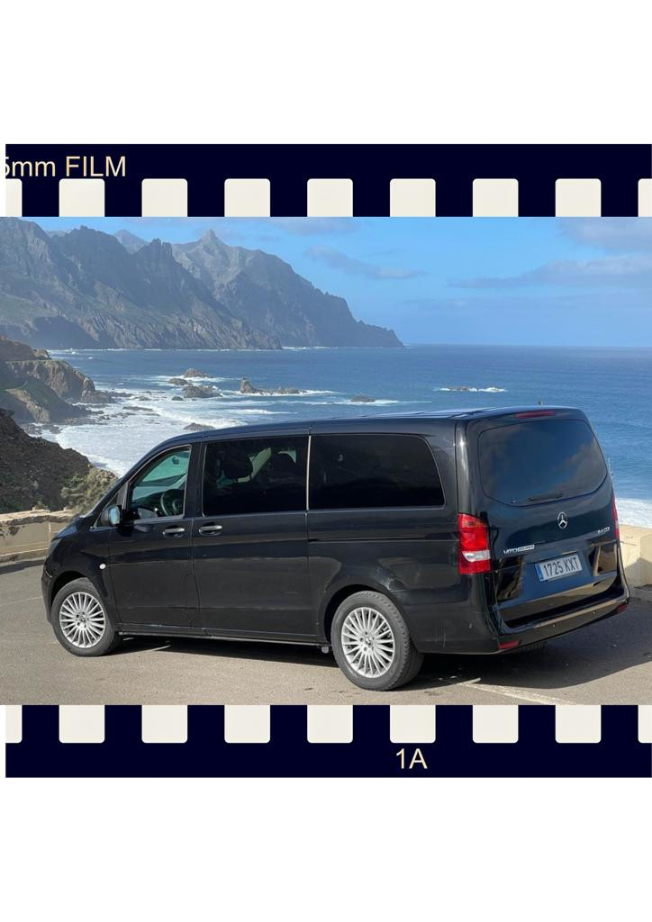 Van negra estacionada frente al mar y montañas en Tenerife. Placa: 1725 KXT.