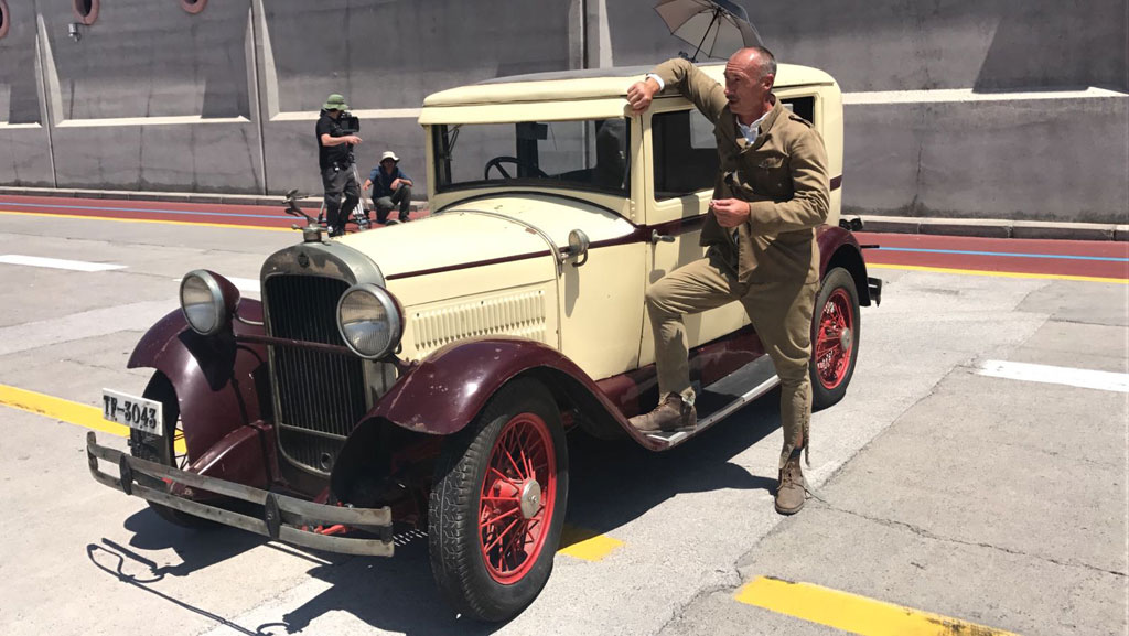 Hombre apoyado en un coche antiguo en una calle de Tenerife.