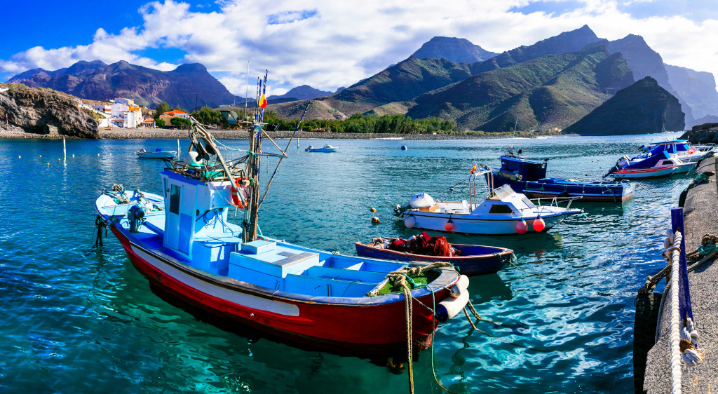 Barcos pesqueros en el Puerto de Agaete, Tenerife, con montañas de fondo.