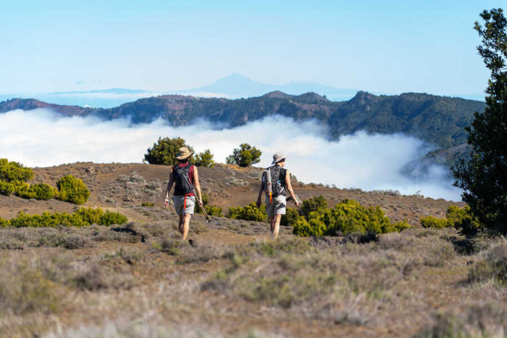 Dos personas caminando entre montañas y nubes en Tenerife.