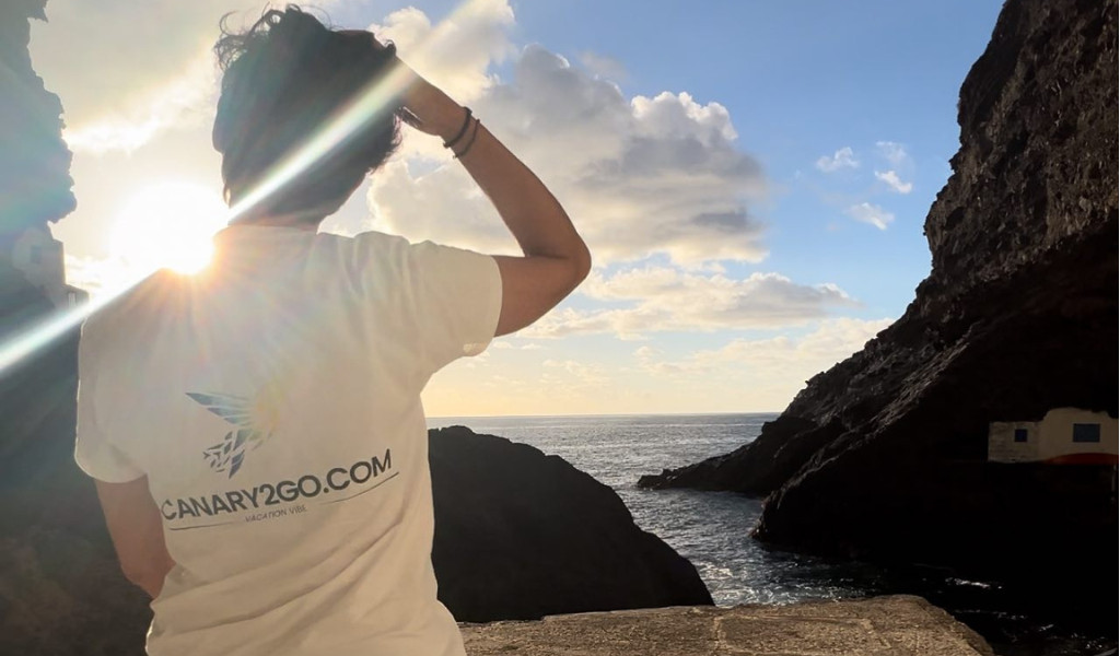 Persona con camiseta CANARY2GO.COM frente al mar y un acantilado en Tenerife.