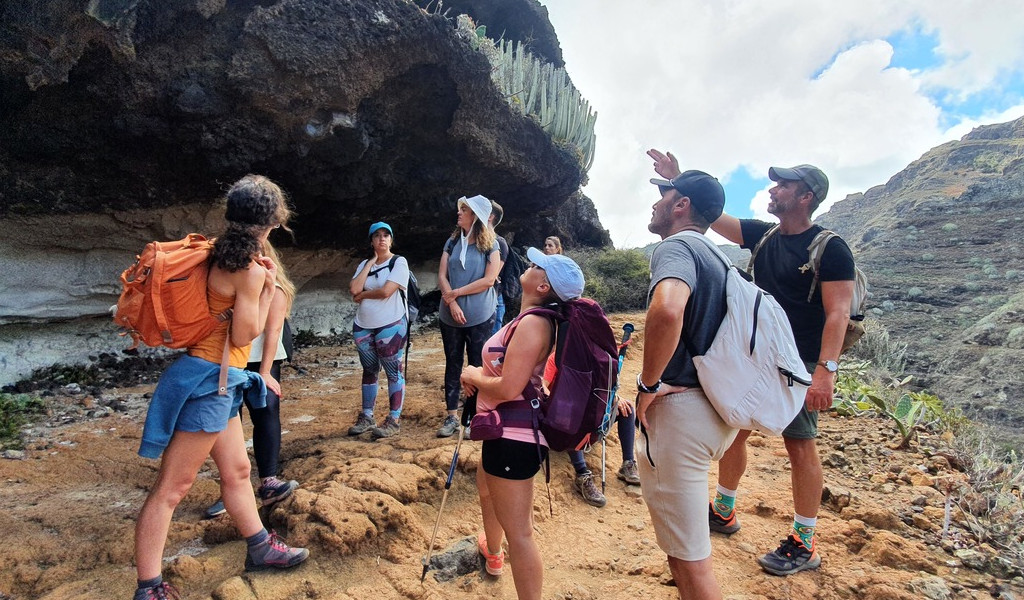Grupo de excursionistas en sendero de montaña en Tenerife, observando el paisaje rocoso.