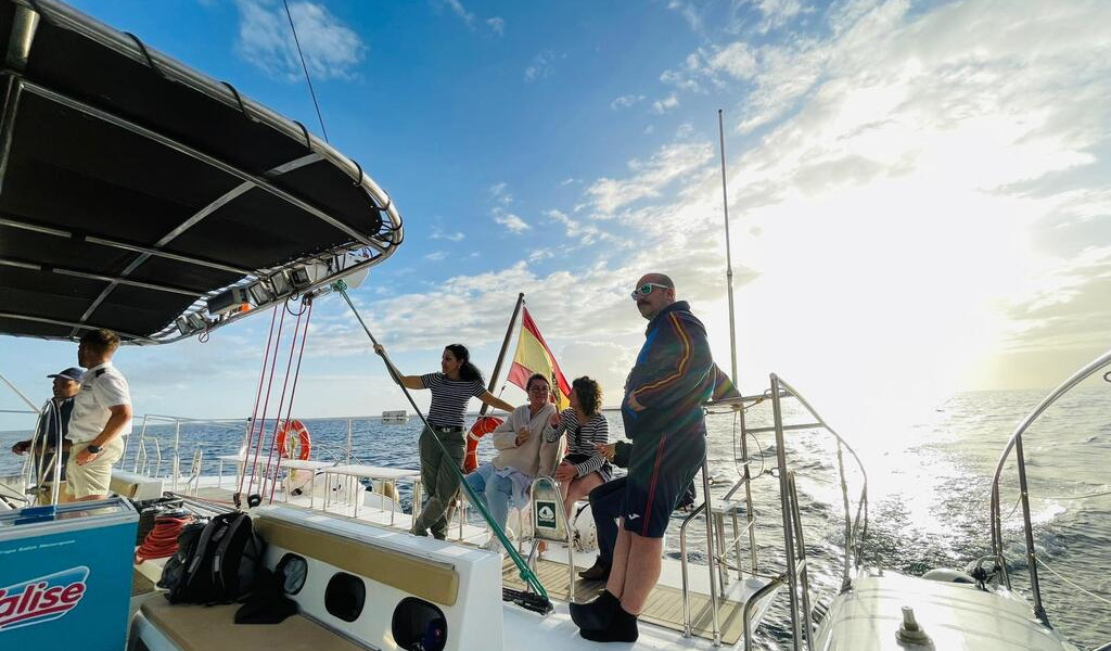 Personas navegando en un barco al atardecer frente a la costa de Tenerife.