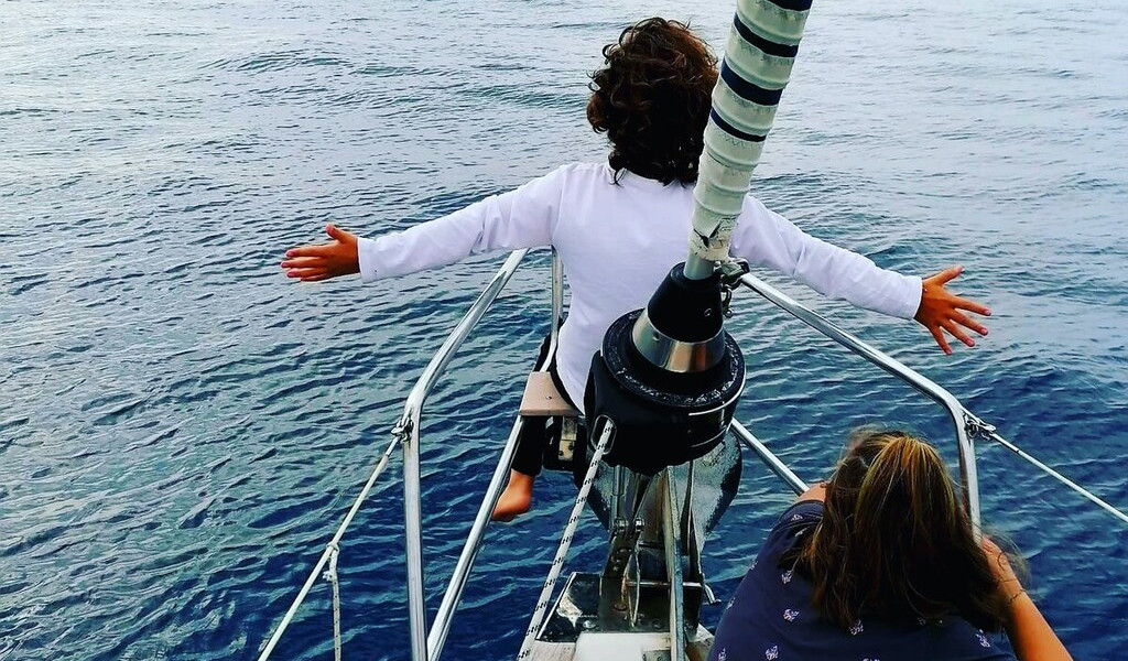 Niños disfrutando en la proa de un velero en el mar de Tenerife.