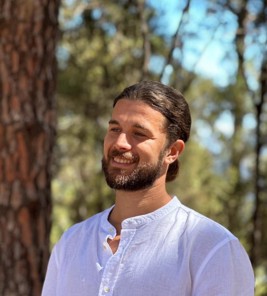 Persona sonriendo en un bosque de Tenerife con camisa blanca.