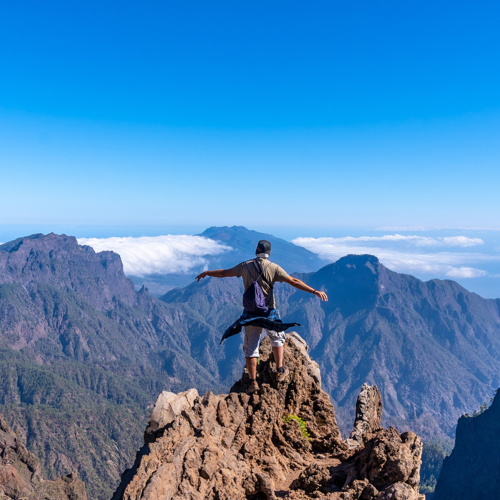 Persona con mochila en cima de montaña con vista a paisajes de Tenerife.