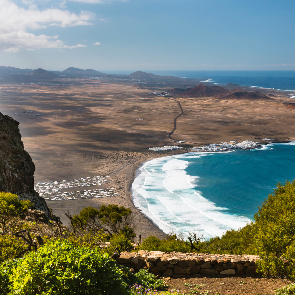 Vista panorámica de la costa con olas rompiendo en una playa arenosa en Tenerife.