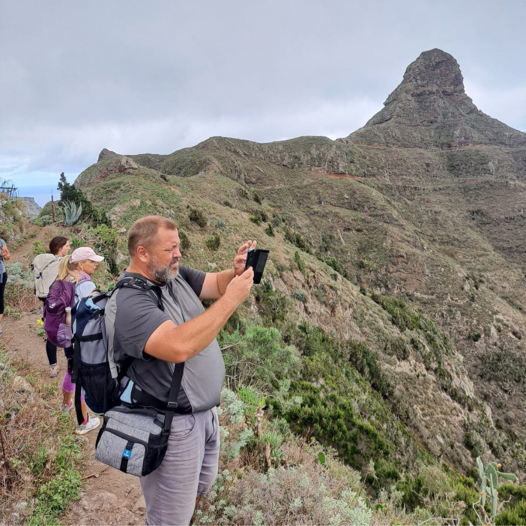 Personas caminando por sendero en Tenerife con montaña de fondo.
