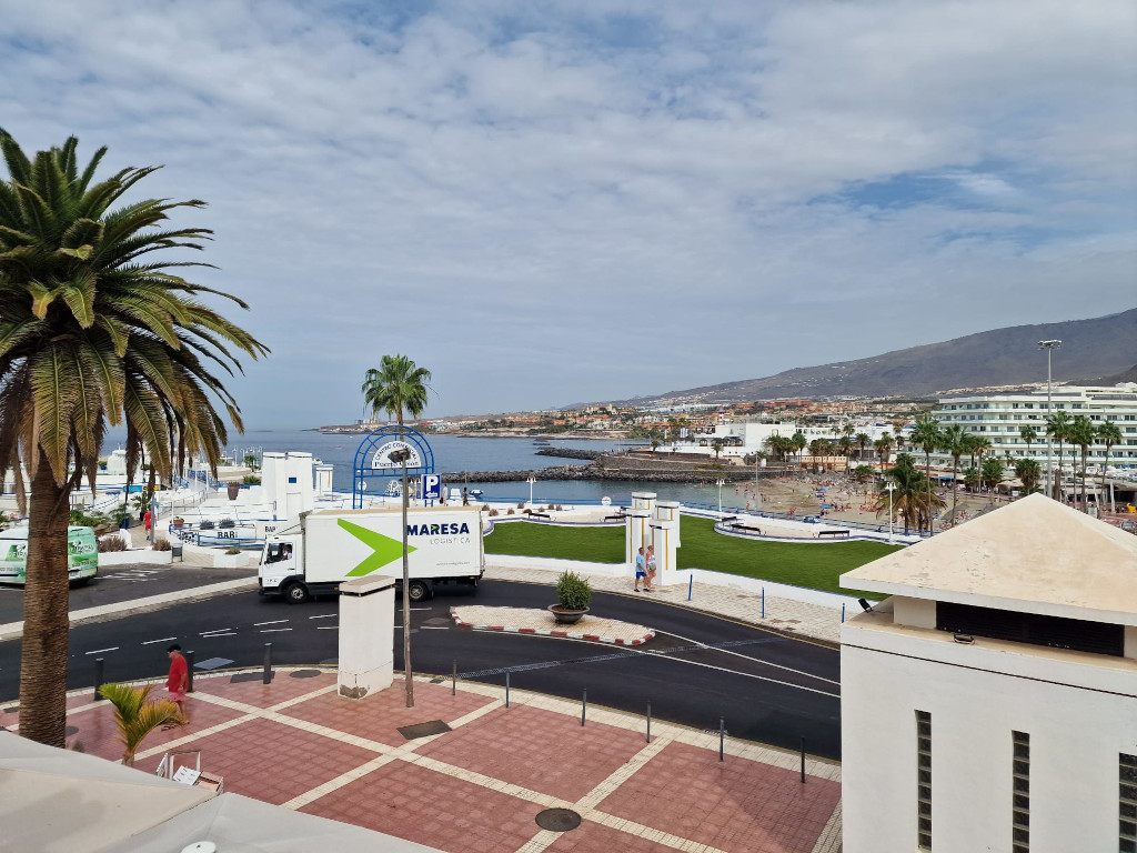 Vistas del puerto de Los Cristianos, Tenerife, con el mar y montañas al fondo.