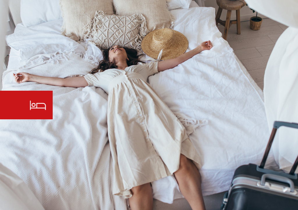 Persona descansando sobre una cama junto a una maleta y un sombrero en Tenerife.