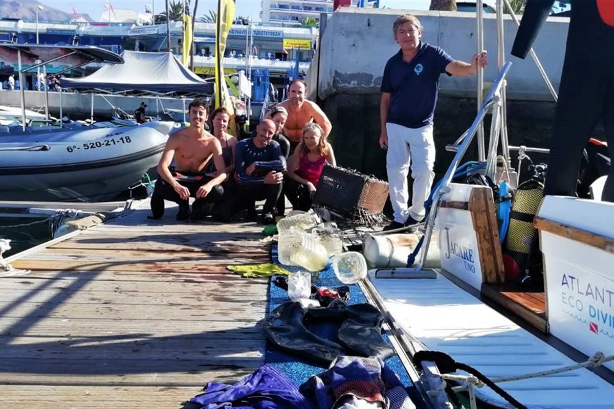 Personas en muelle con equipo de buceo y basura recolectada en Tenerife.